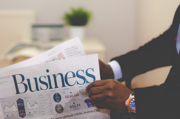 A business man combs through the business section of a newspaper at his consulting business